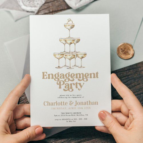 two hands holding a card with champagne glasses on it and the words engagement party written in gold