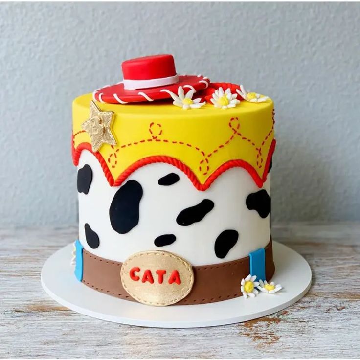 a cake decorated with a cow theme and name on the top is sitting on a plate