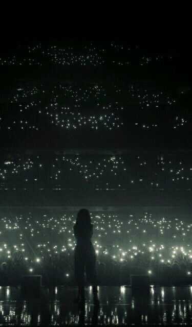 a person standing in front of a large amount of lights on a dark night sky