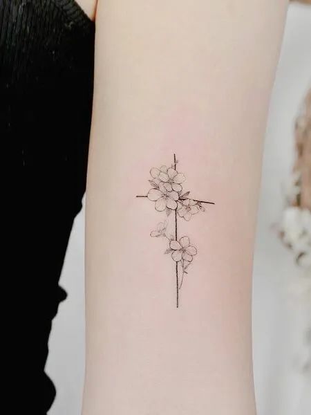 a small cross and flower tattoo on the left side of the right arm is shown