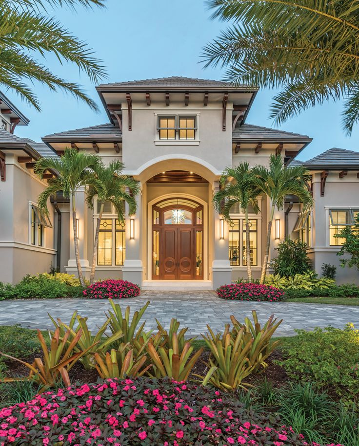 a large house with palm trees in front of it and landscaping around the entry door