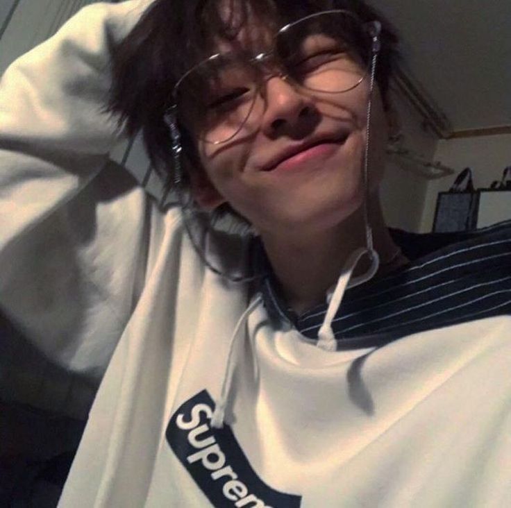 a young man wearing glasses and a supreme sweatshirt