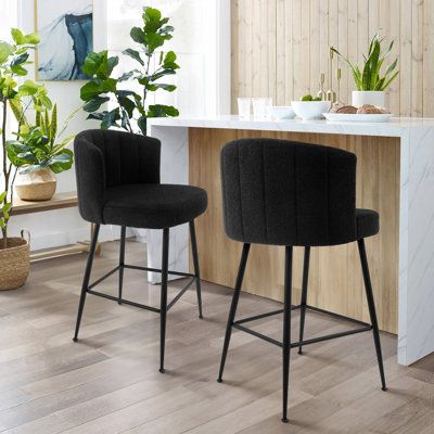 two black bar stools sitting in front of a counter