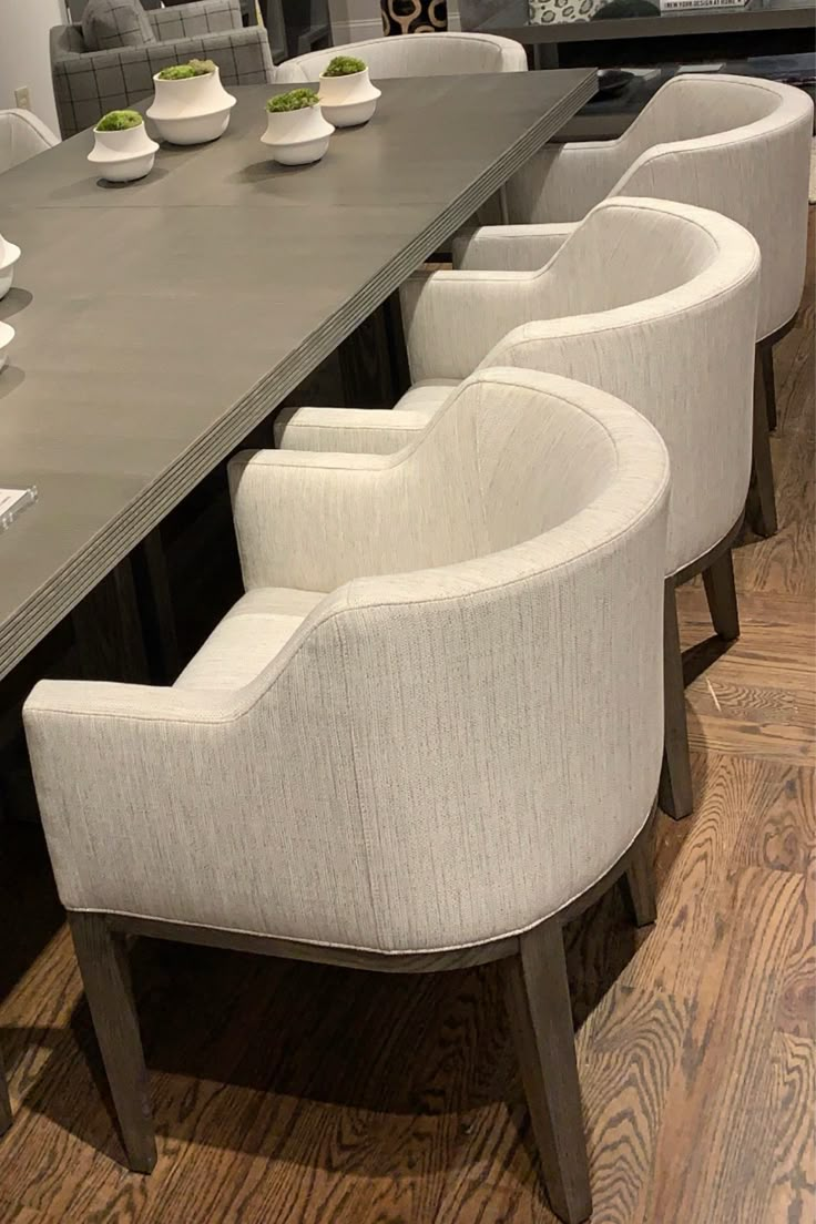 a long table with white chairs and plates on it in a room that has hardwood floors