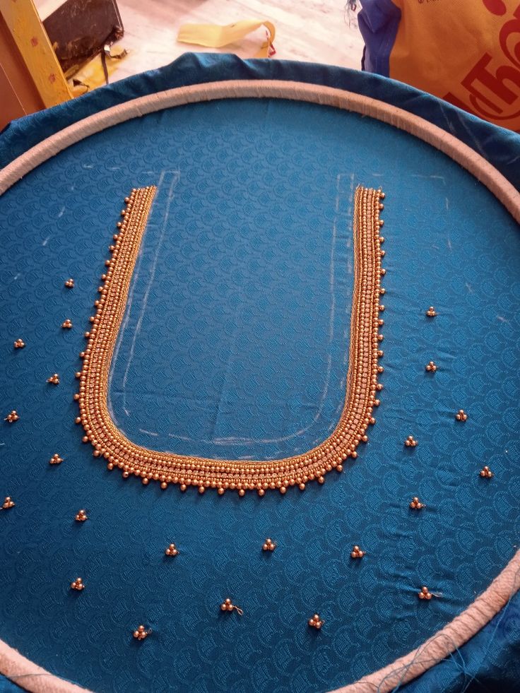 a blue cloth with gold beading on it and a circular object in the background