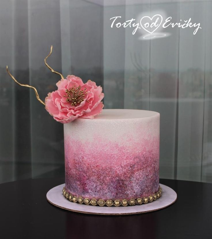 there is a pink and purple cake with a flower on the top that has been decorated