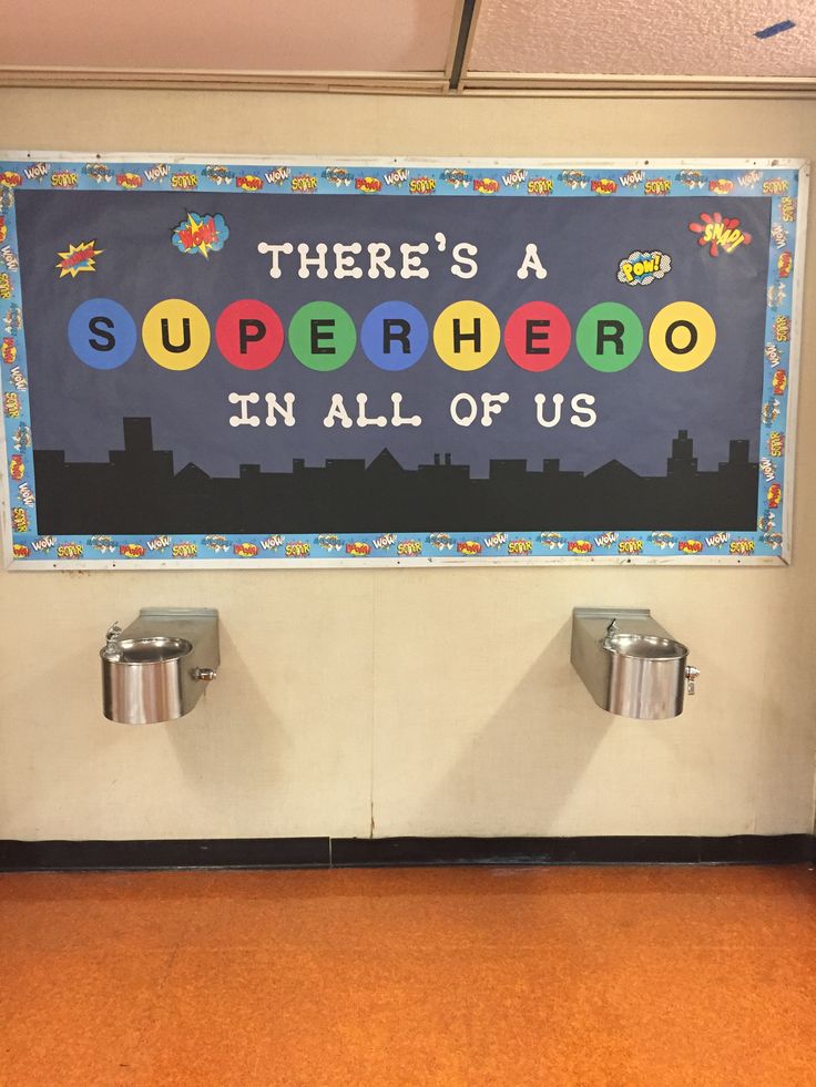 there's a superhero in all of us sign on the wall above two urinals