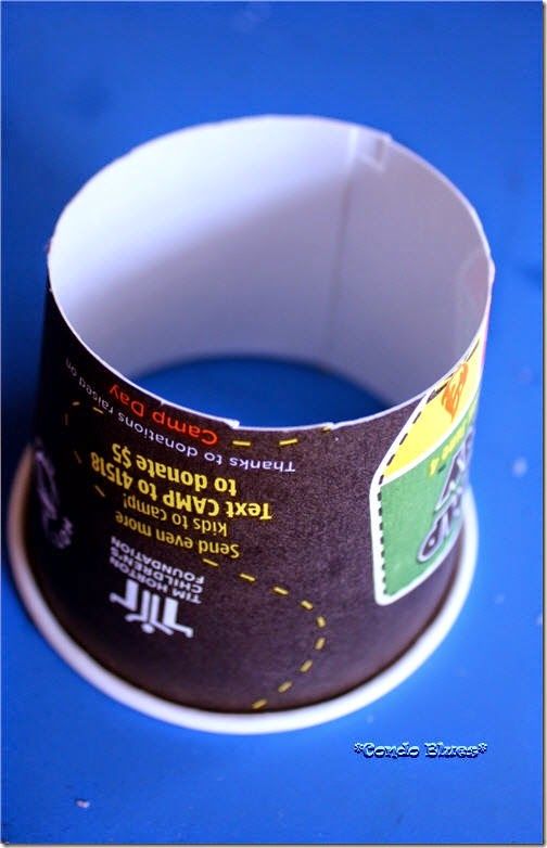 a close up of a paper cup on a blue surface with the bottom half cut off