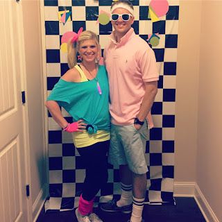 a man and woman standing in front of a checkered wall with balloons on it