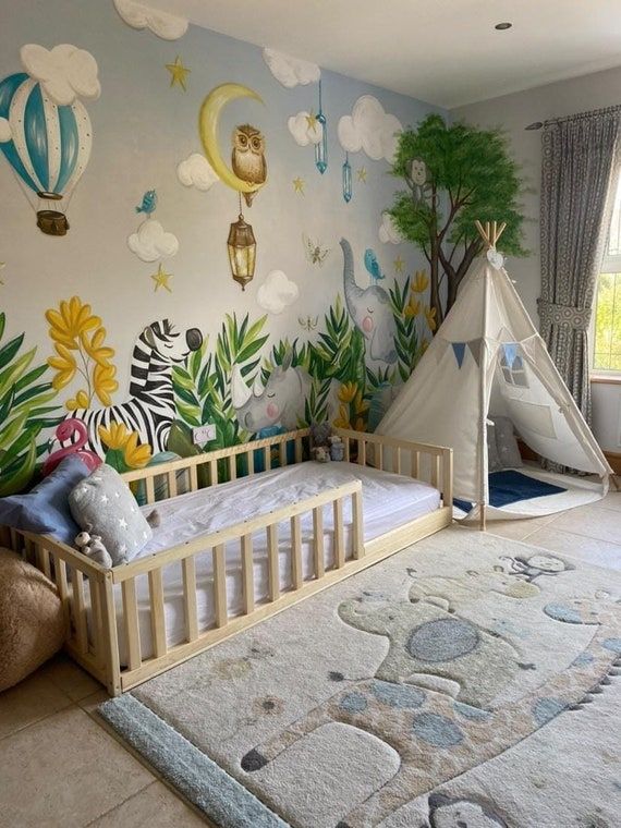 a child's bedroom with a teepee tent and wall mural