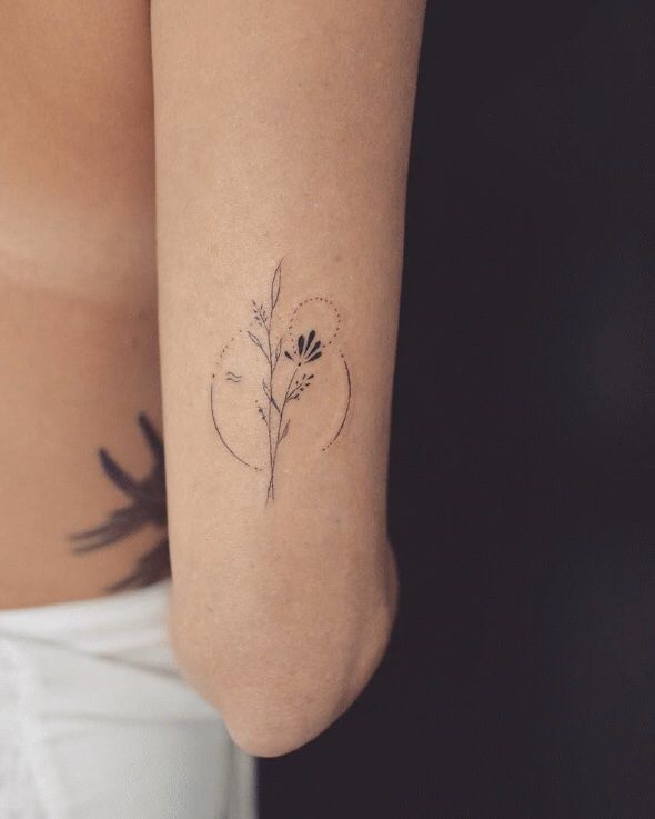 a woman's arm with a small flower tattoo on the left side of her body