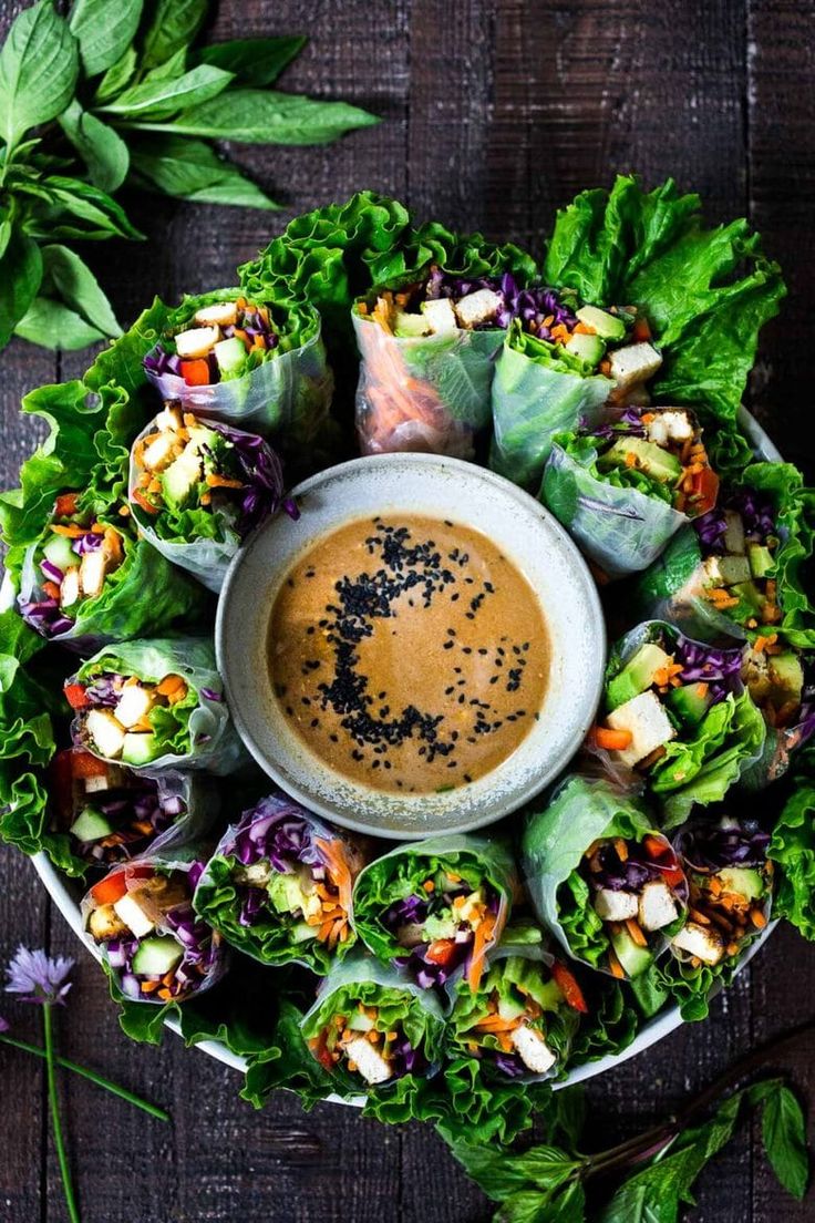 a plate filled with lettuce wrapped in sauce next to some other vegetables and garnishes