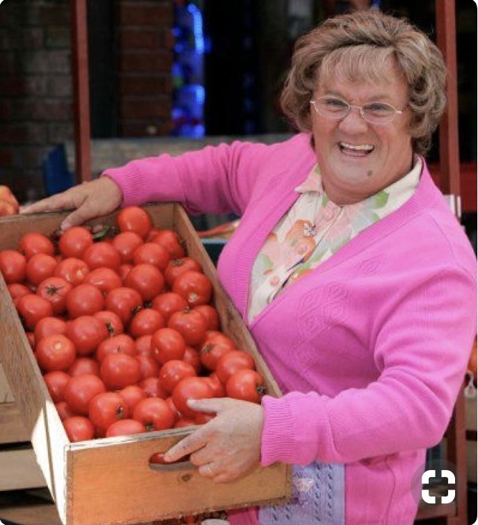 a woman holding a box full of tomatoes