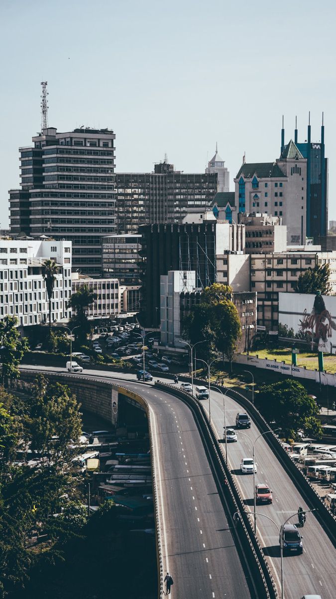 an aerial view of a city with tall buildings and cars on the road in front of it