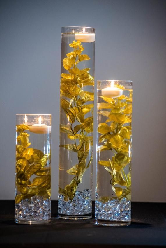 three clear vases with yellow flowers in them