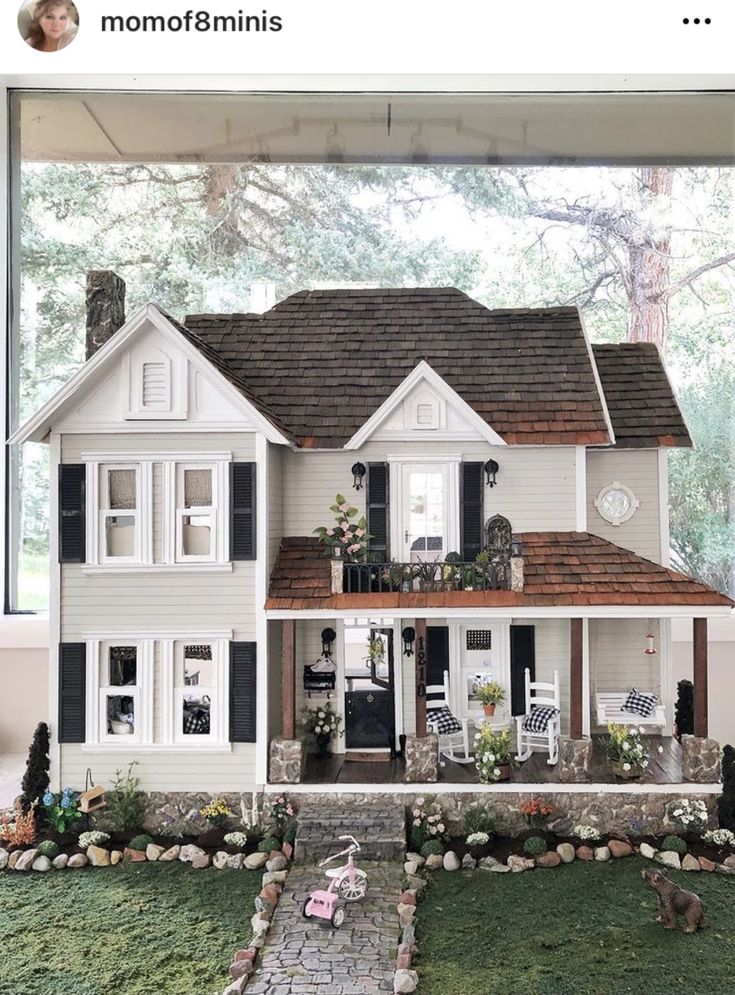 a doll house is shown in front of a window with grass and rocks on the ground