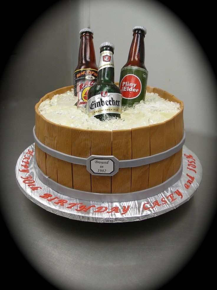 a cake made to look like a barrel with beer bottles on top and frosting around it