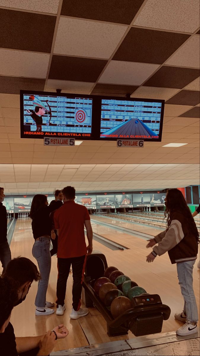 several people are standing around at the bowling alley