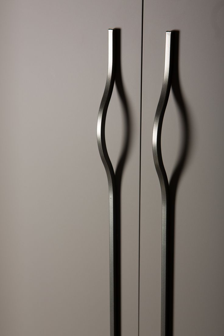 two tall black metal doors in front of a gray wall with an abstract design on it