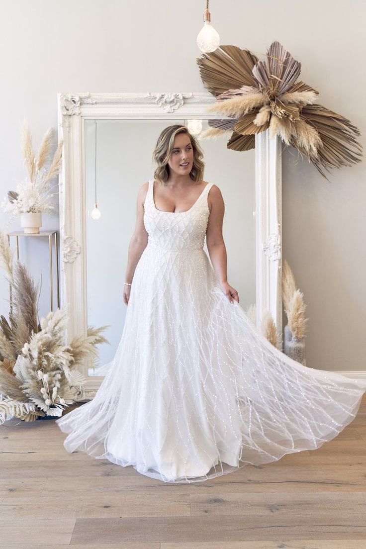 a woman standing in front of a mirror wearing a white dress