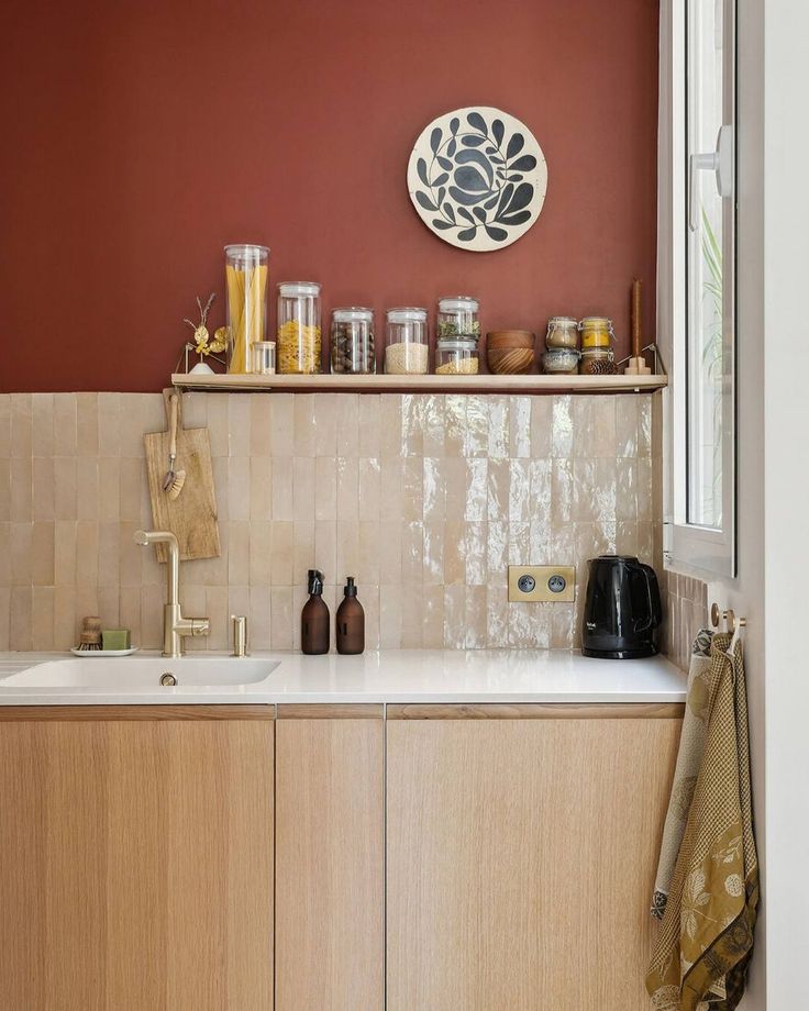 a kitchen with red walls and white counter tops, wooden cabinets and open shelves on the wall