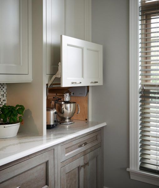 a kitchen with white cupboards and a bowl on the counter next to a window