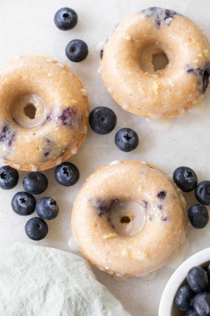 three doughnuts with blueberries are on the table