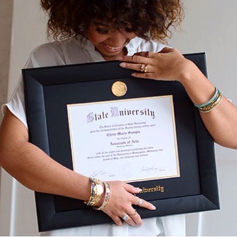 a woman is holding up a framed diploma