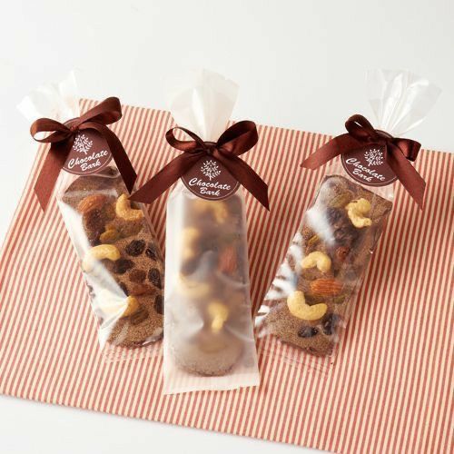 three bags filled with nuts on top of a red and white striped table cloth next to each other