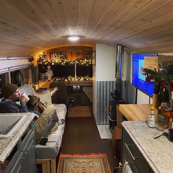 a man sitting on a couch in a living room next to a kitchen and dining area