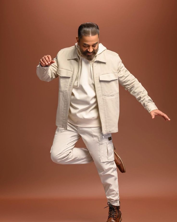 a man in white pants and jacket is doing a dance move with his hands out