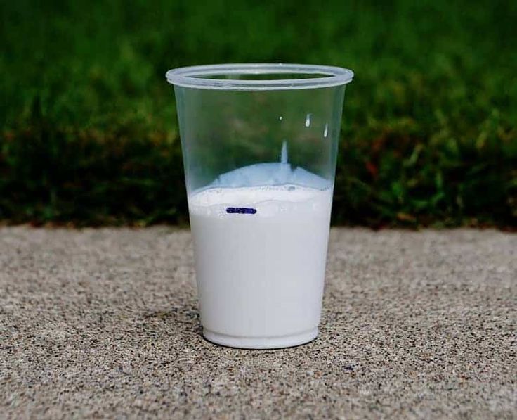 a glass filled with milk sitting on the ground