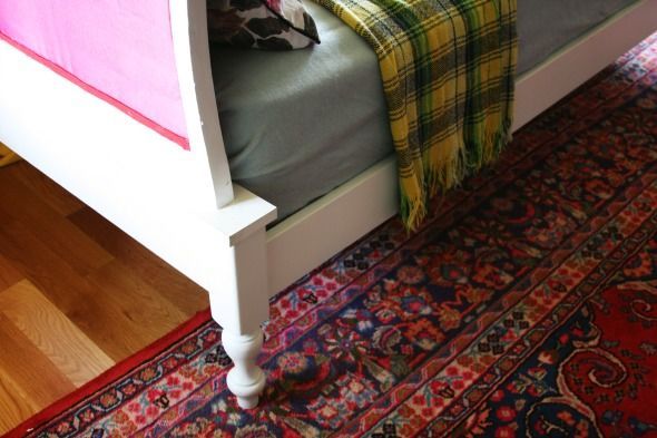 a dog laying on top of a bed next to a rug