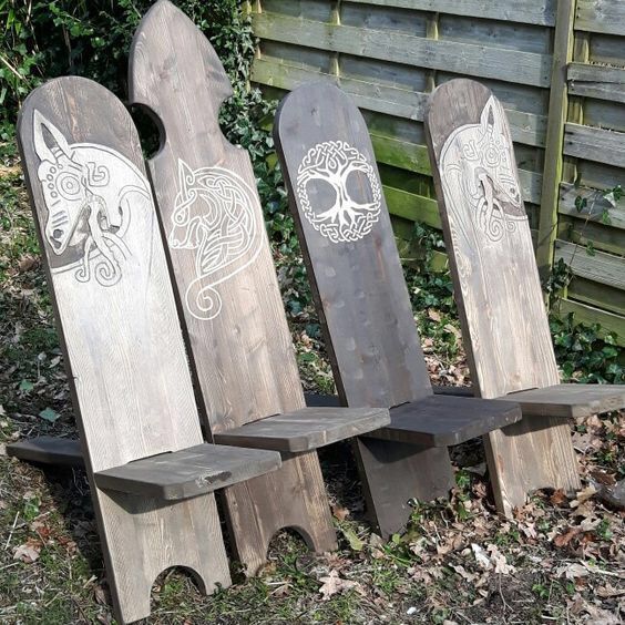 three wooden benches with carved designs on them in front of a fenced yard area