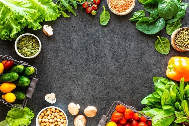 many different types of vegetables and fruits on a black surface with space in the middle