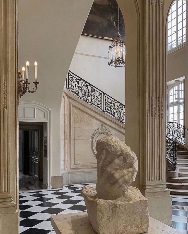 a marble sculpture sitting on top of a checkered floor in front of a staircase