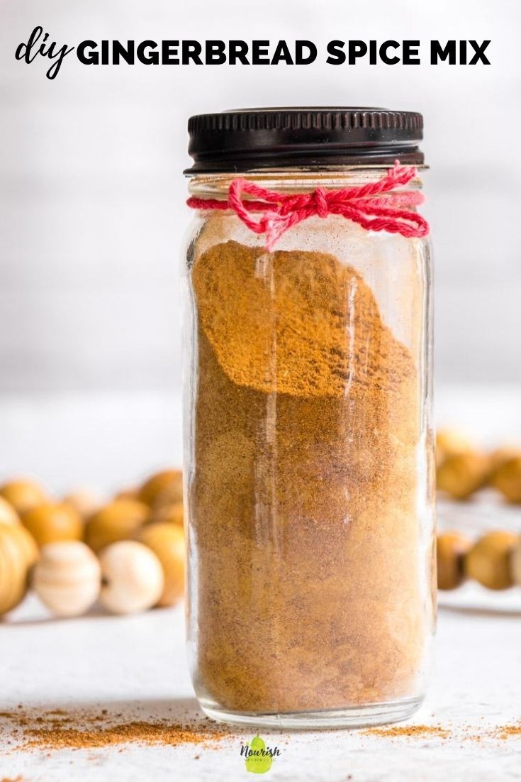 a glass jar filled with cinnamon spice on top of a white table next to wooden beads