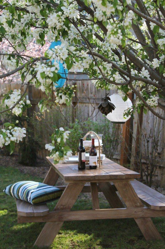 a picnic table in the backyard with bottles of wine on it