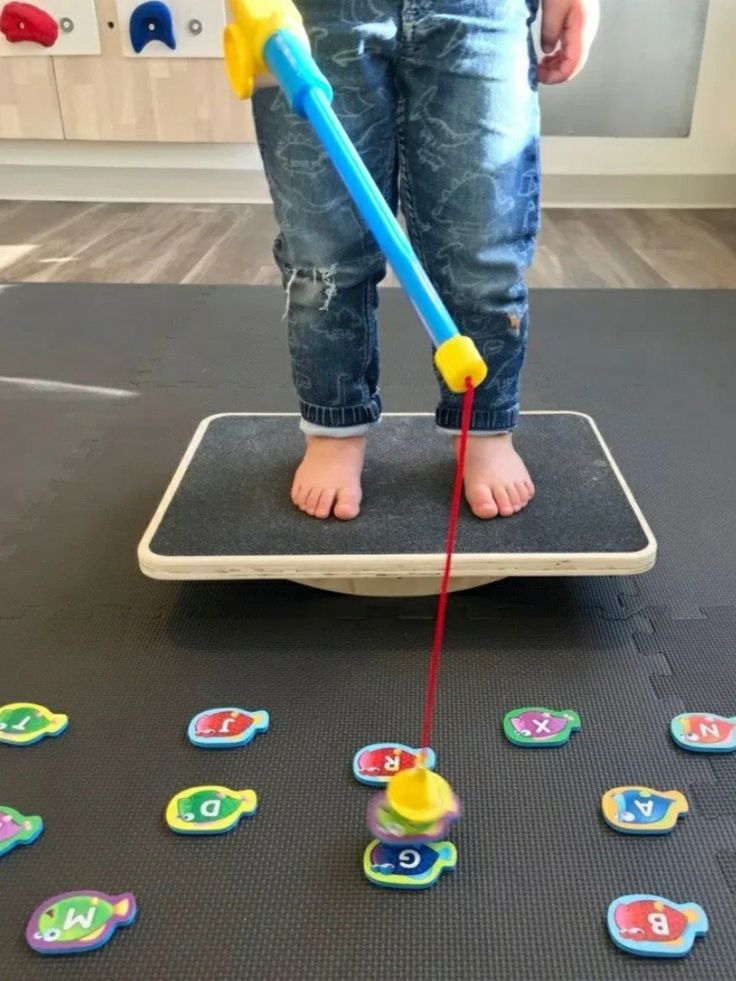 a young child standing on top of a balance board with letters and numbers around it