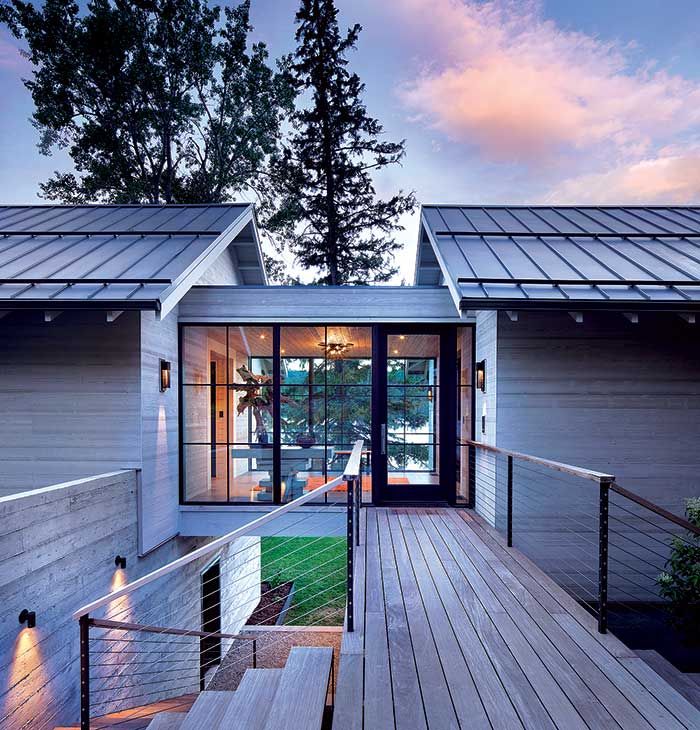 a wooden deck leading up to a house with glass doors on the front and side