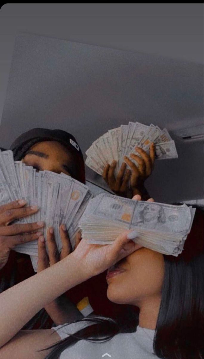 two people holding up stacks of cash in front of their faces