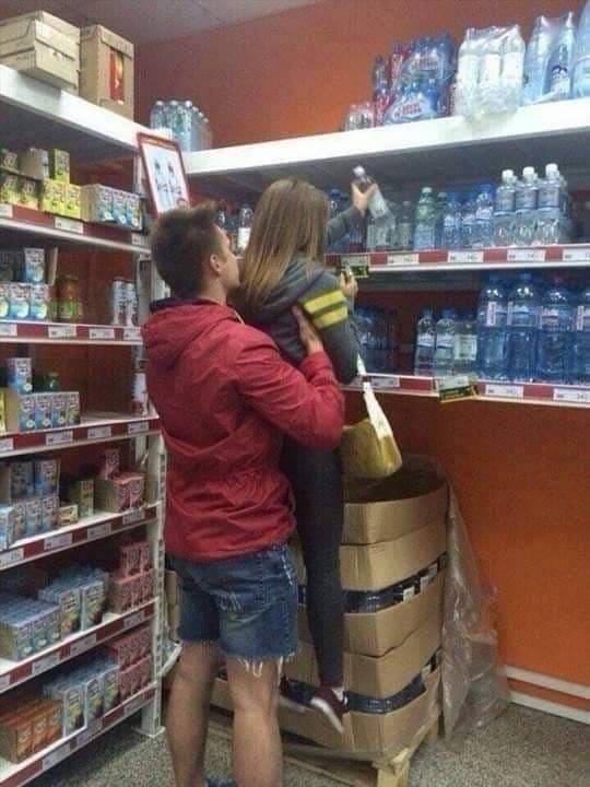 a man and woman standing in front of a grocery store shelf with bottled water behind them