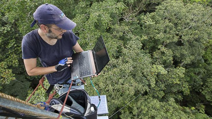 a man standing on top of a metal structure with a laptop computer in his hand