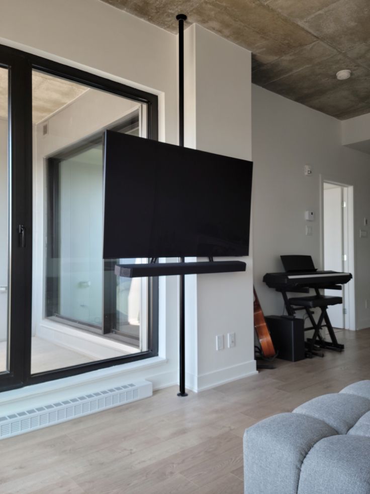 a flat screen tv mounted to the side of a wall in a living room next to a window