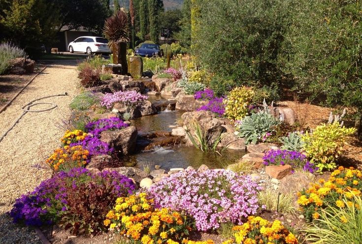 a car is parked next to a garden with rocks and flowers in the foreground