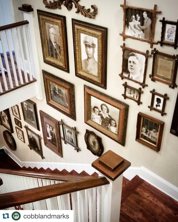 a staircase with many framed pictures on the wall and wooden banisters above it