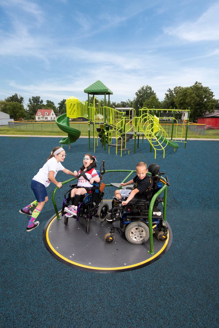 three people in wheelchairs playing on a playground