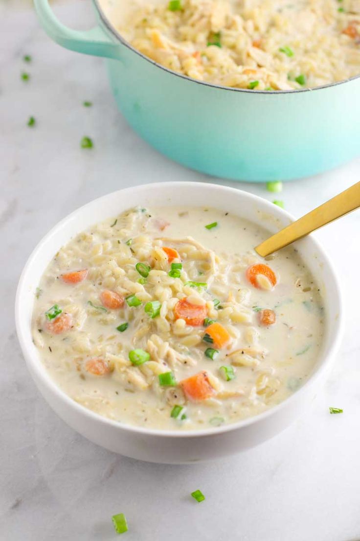 a bowl of chicken pot pie soup next to a blue casserole dish on a white counter