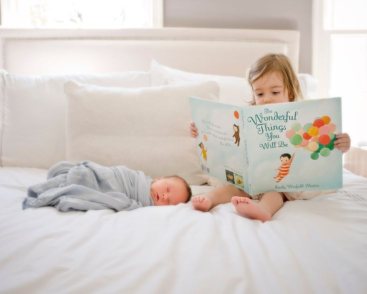 two children laying on a bed reading a book