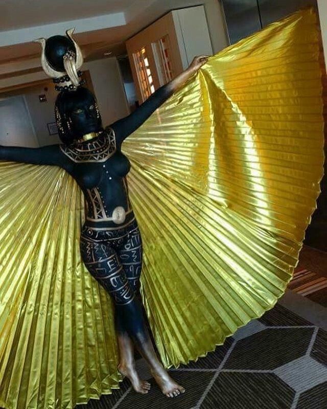 a woman dressed in black and gold holding a yellow fan